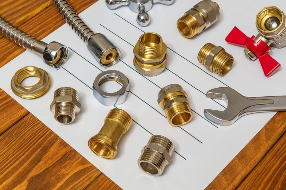 Brass plumbing fittings and a pipe wrench laid out on a bench.