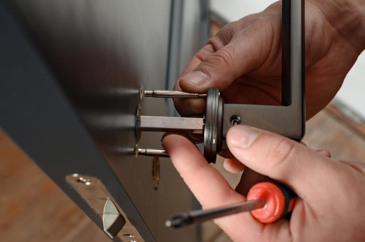 Hands setting a doorknob spindle through a door.