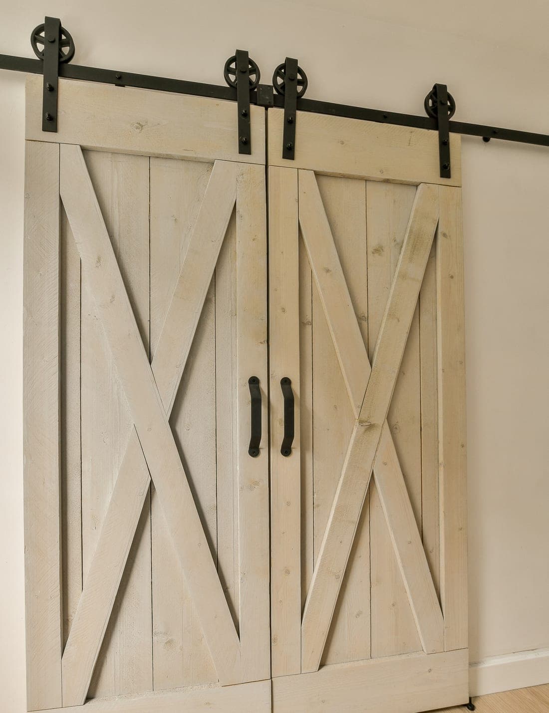 Cast-iron sliding door hardware and track on a pale timber door.